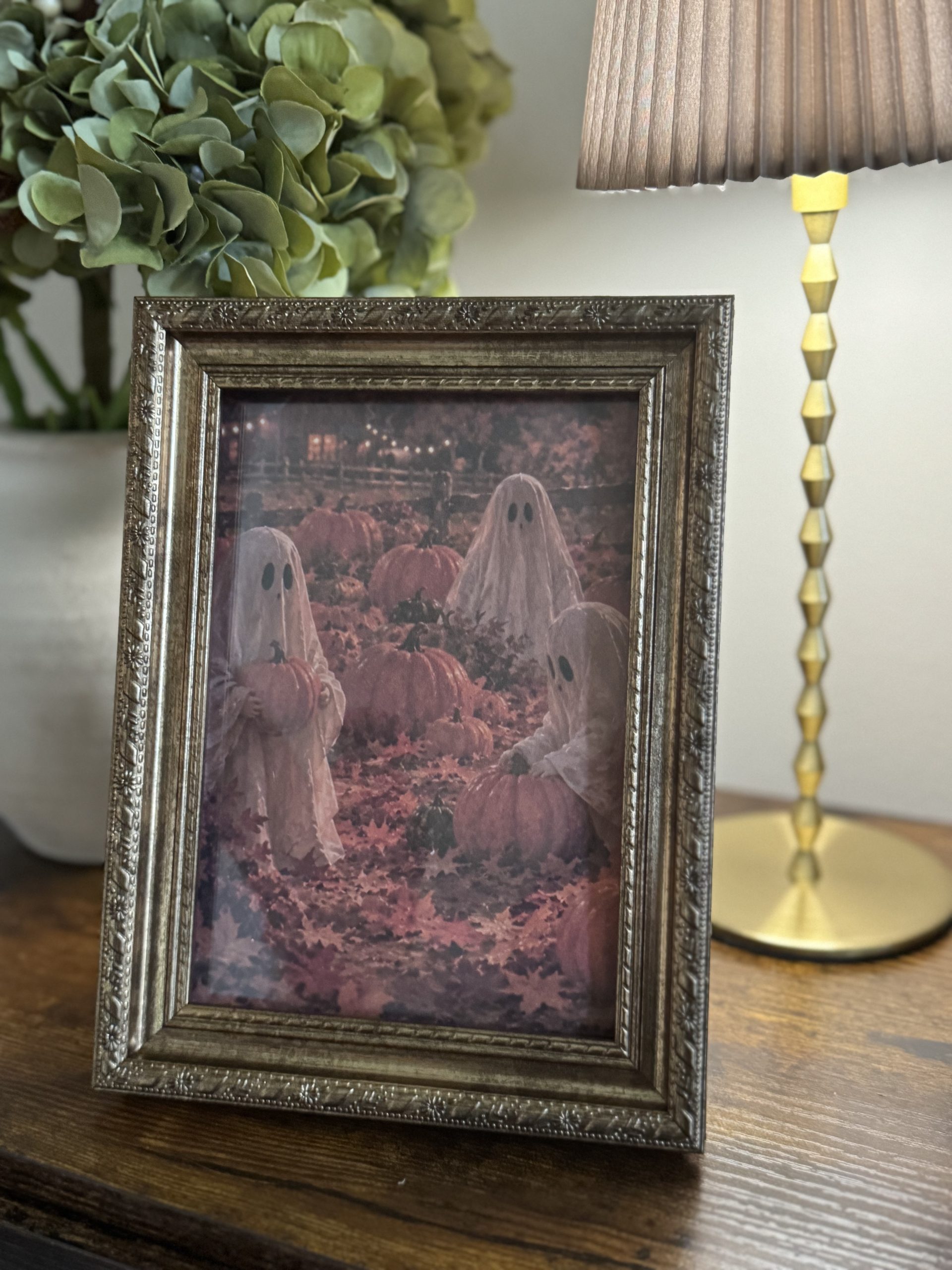 Free printable fall art ghosties in a pumpkin patch print in gold frame on entryway table